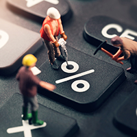 Miniature model workers standing on a black calculator keypad around the percentage key